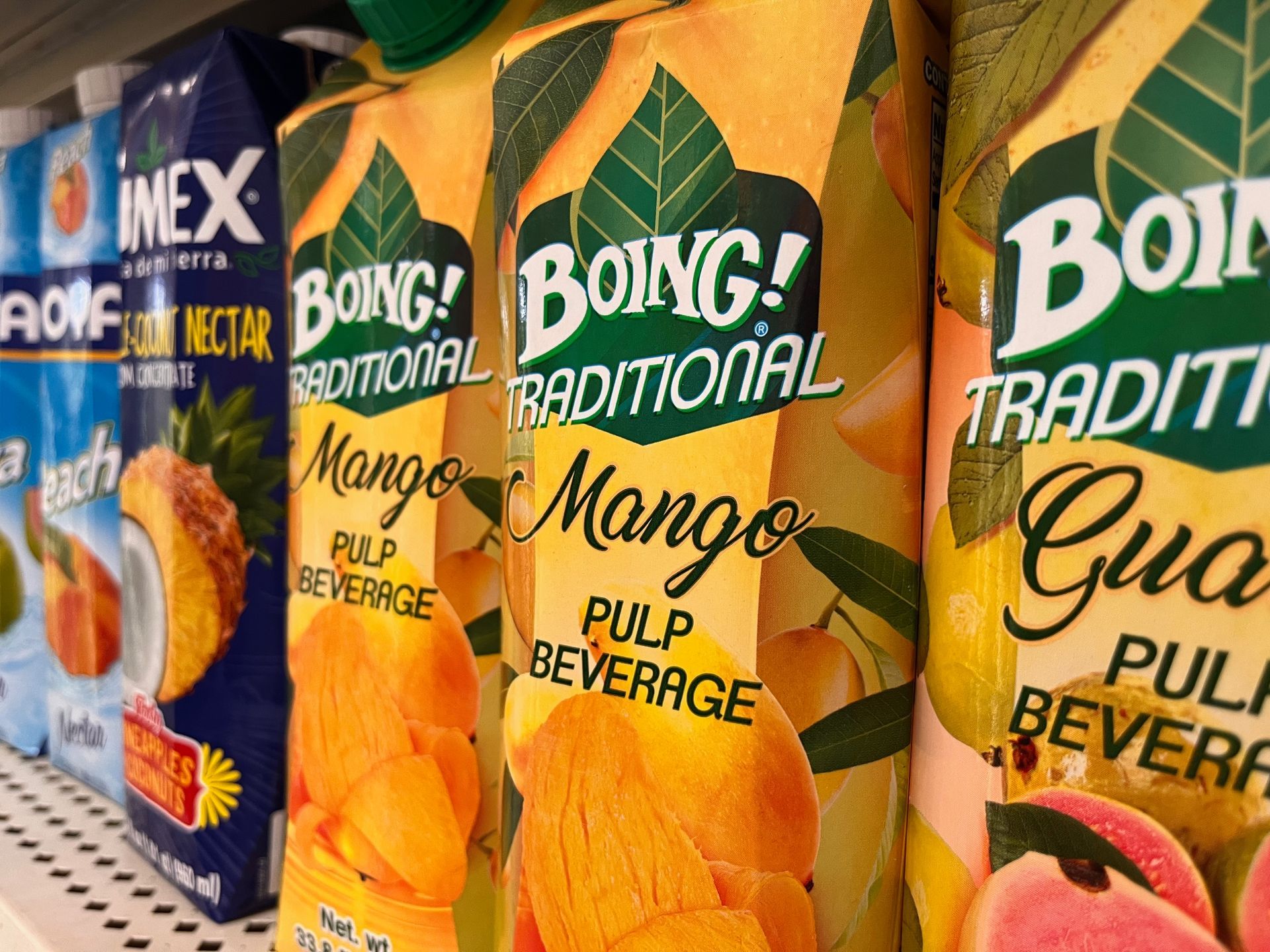 Several boxes of boing traditional mango pulp beverage are lined up on a shelf