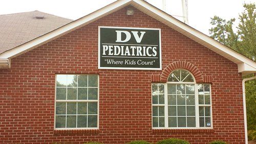 Brick building with a DV Pediatrics sign and windows, shown from outside.