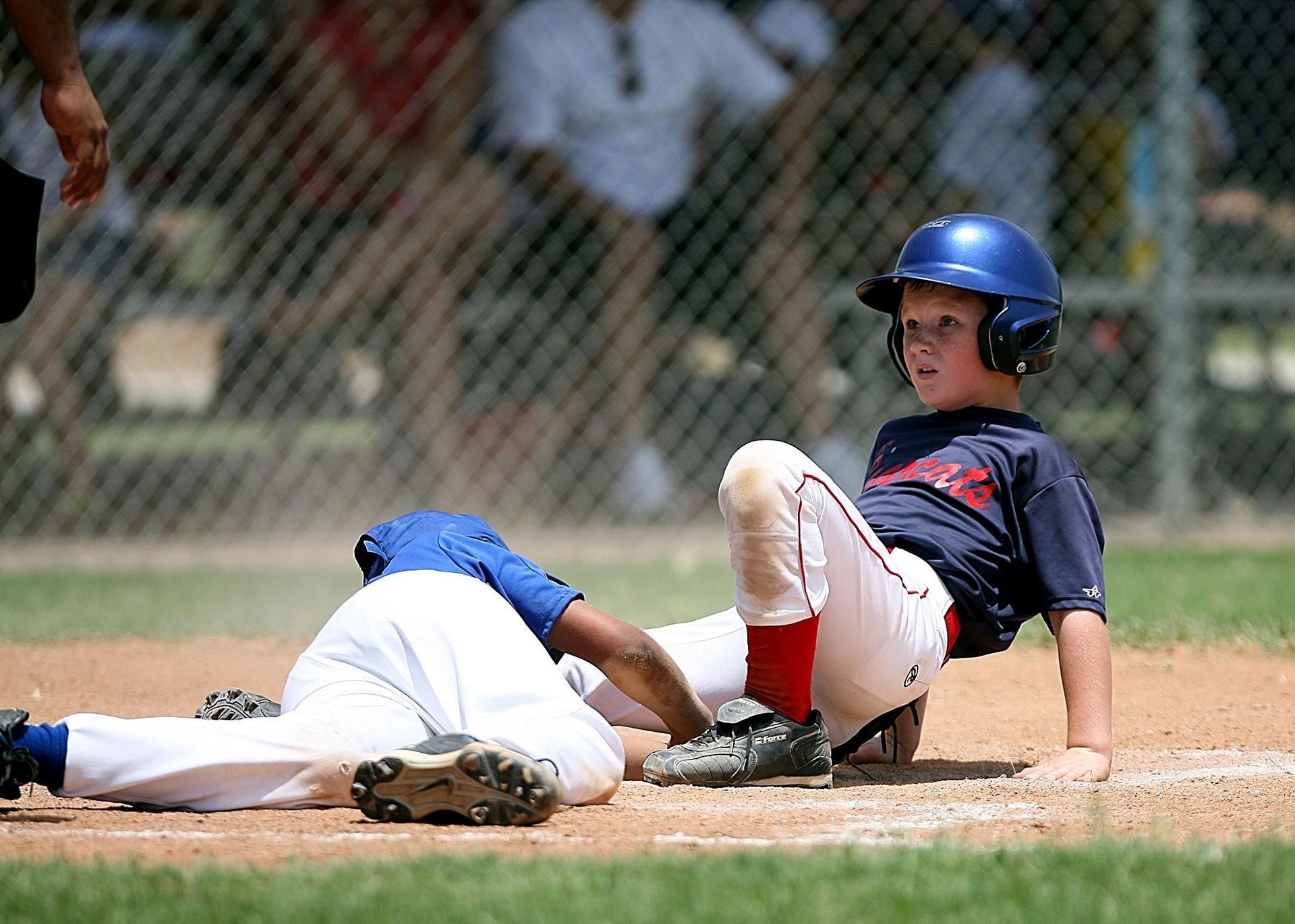 Baseball player sliding into home plate as the catcher tags him on a dirt field