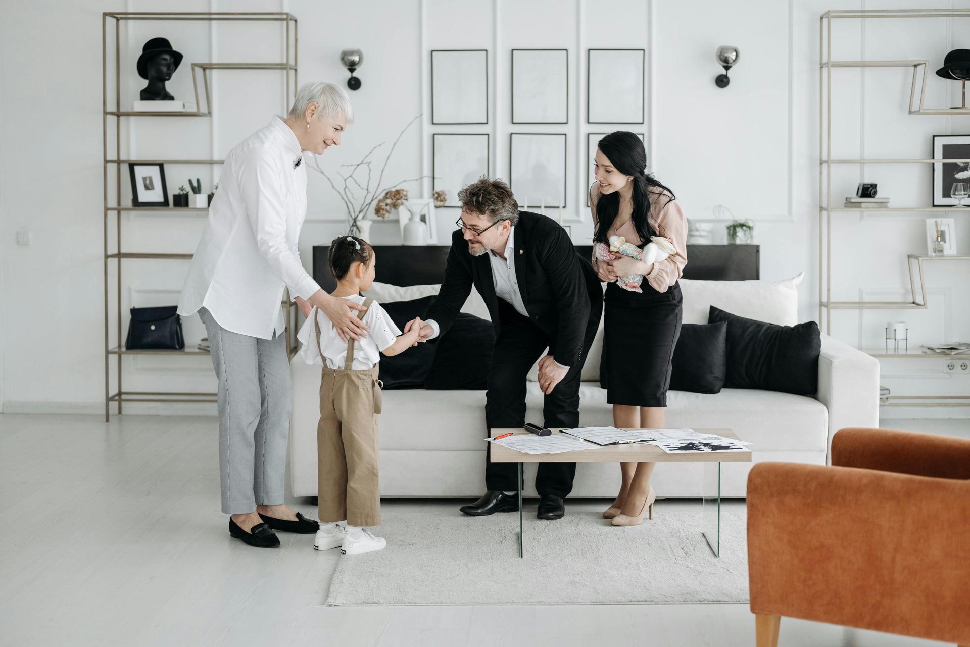 People discussing a document in a bright living room with shelves and a sofa.