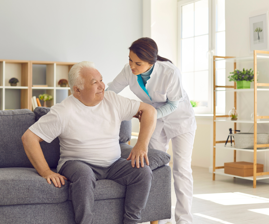 Caregiver helping person sit up on a couch indoors.