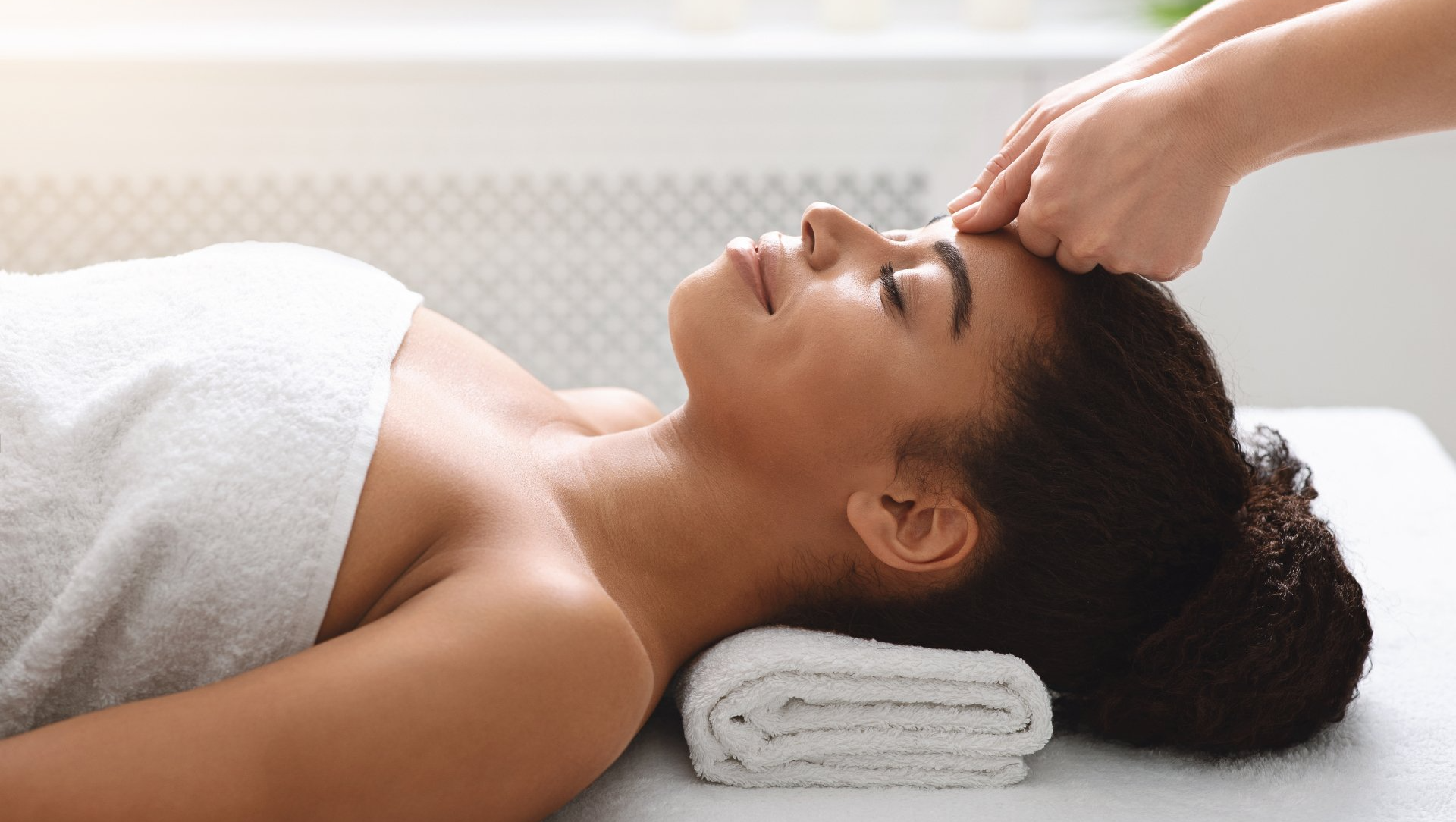 A black woman smiles as her forehead is massaged