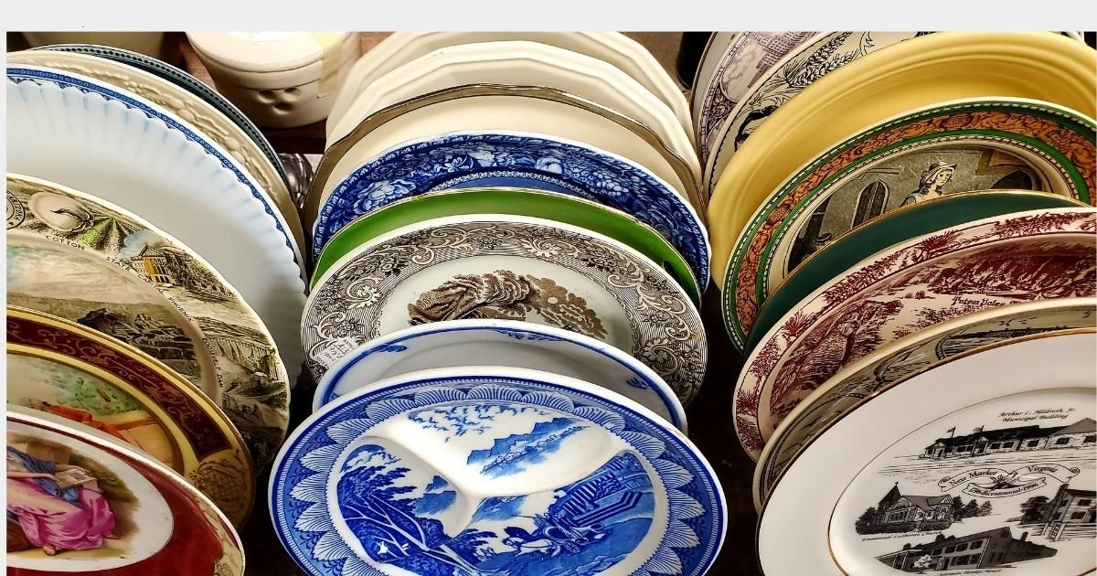 Stacked decorative plates in various colors and patterns displayed on shelves