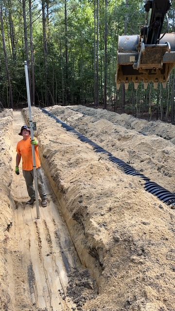 A man is digging a trench in the dirt with a shovel.