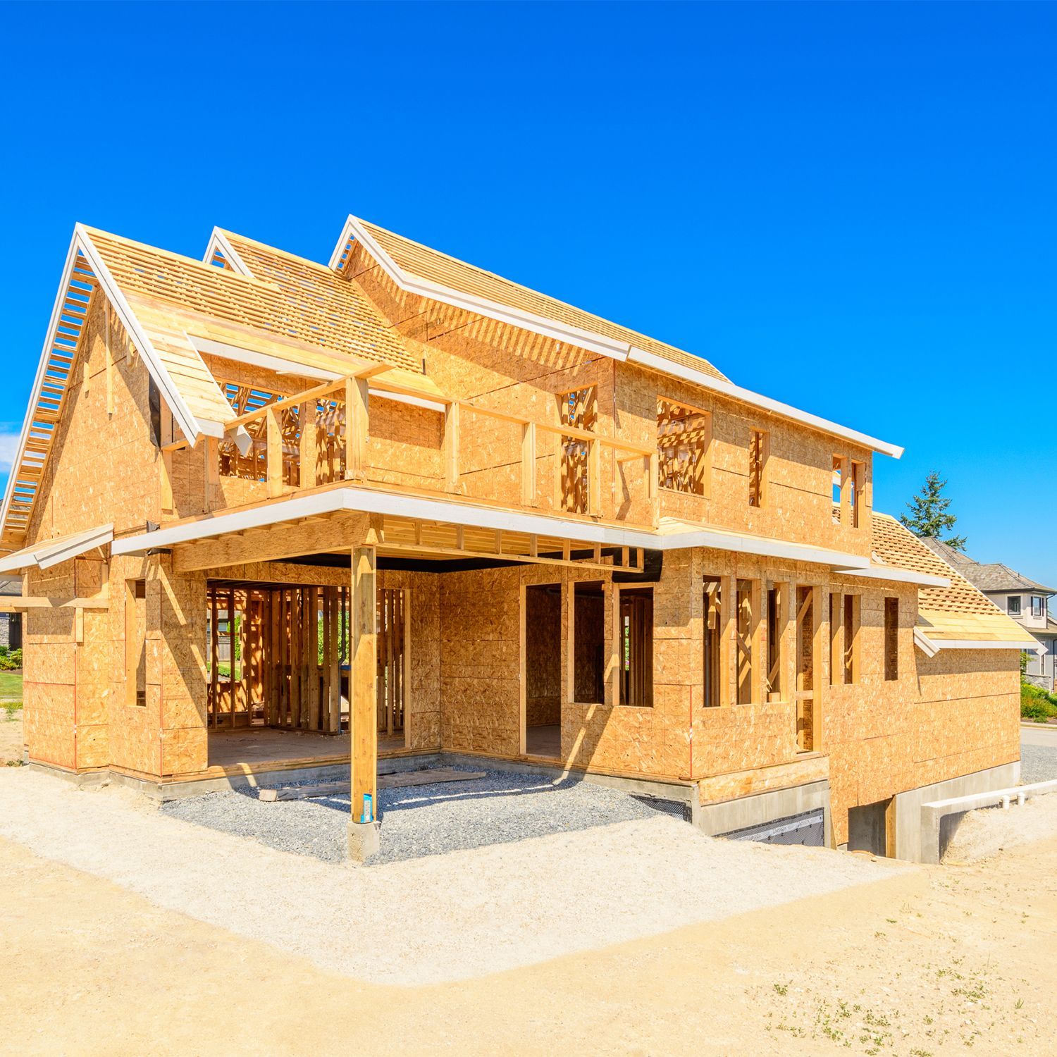 Estructura de casa de madera en construcción, con ventanas abiertas y cielo azul claro.