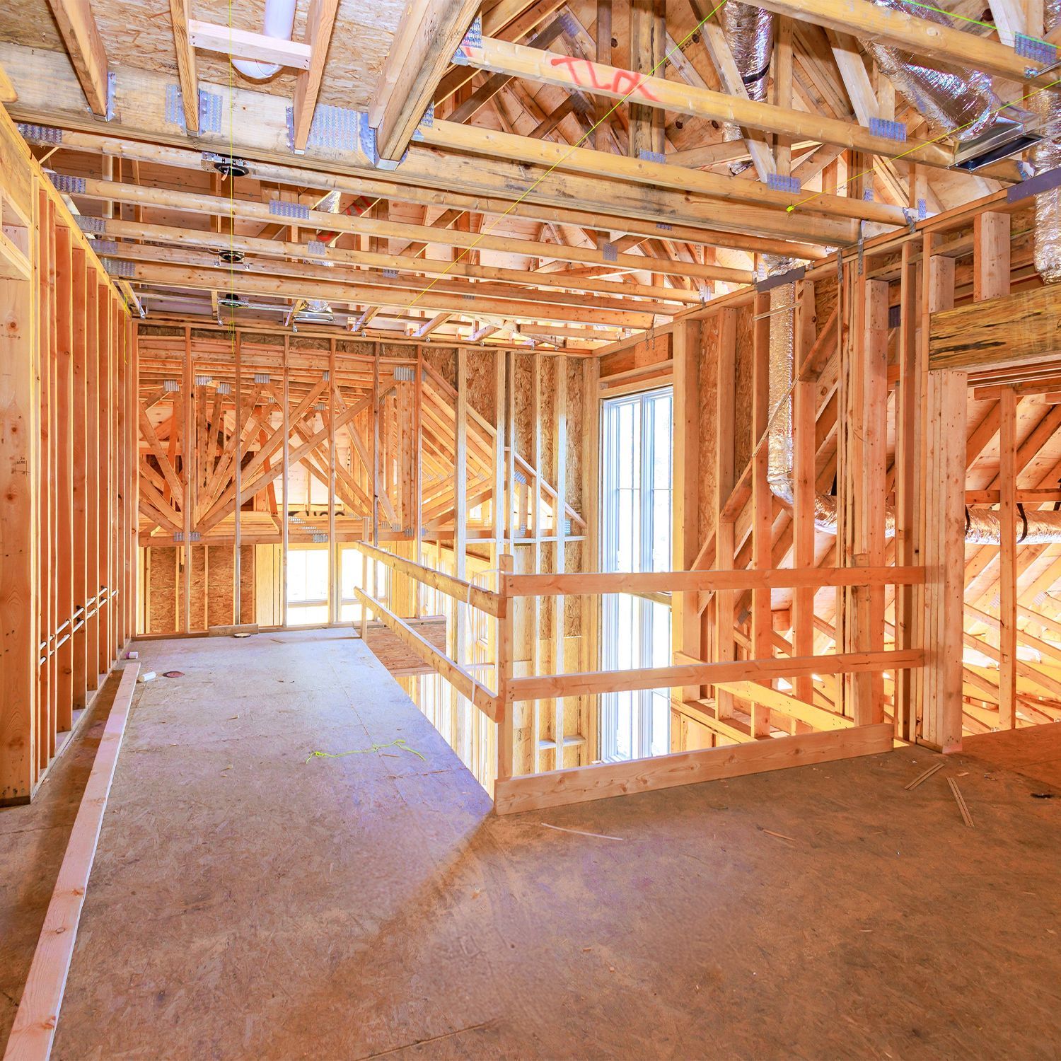Vista interior de un edificio en construcción, mostrando estructura de madera y pisos y techos sin terminar.