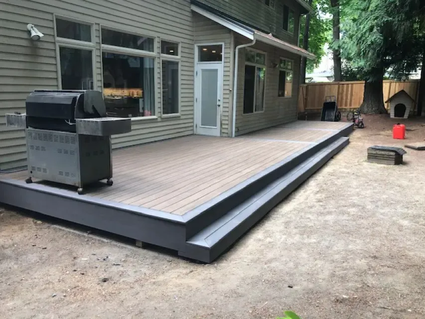 Wooden deck with a built-in step, charcoal grill, and a house in the background.