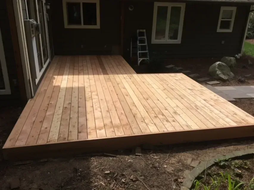 Newly constructed wooden deck attached to a dark-colored house.