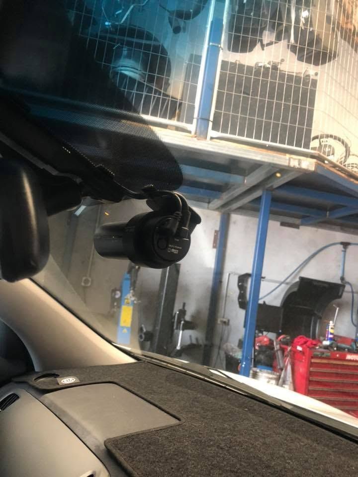 Car interior facing a garage with blue shelving, wire cages, and red tool drawers. Car interior facing a garage with blue shelving, wire cages, and red tool drawers.