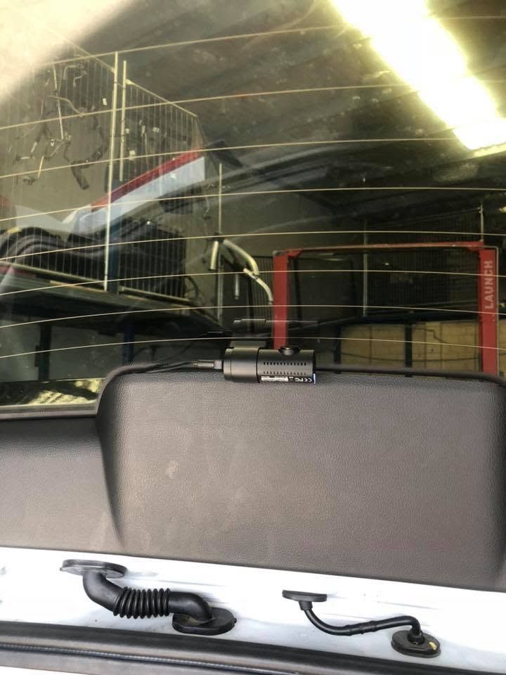 Back seat view of a car interior, with a seatback, rear window, and fluorescent lights outside Back seat view of a car interior, with a seatback, rear window, and fluorescent lights outside