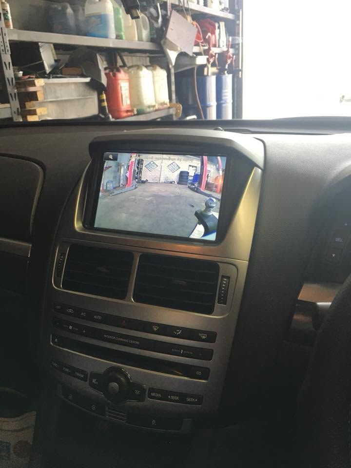 Car dashboard with built-in screen showing a garage view and shelves in the background. Car dashboard with built-in screen showing a garage view and shelves in the background.