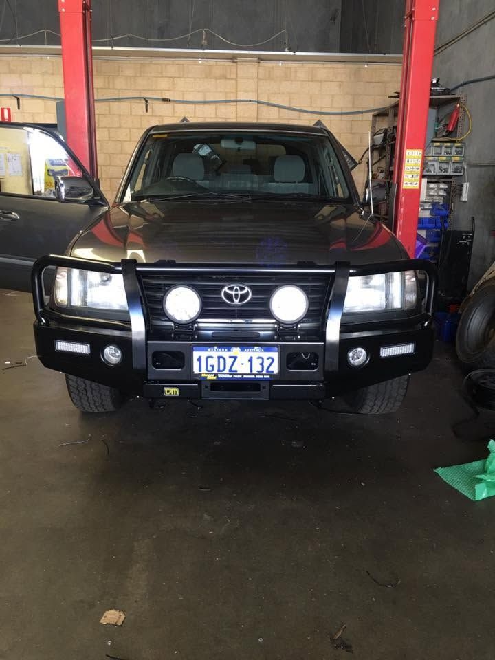 Black Toyota SUV in a garage with bull bar, spotlights, and front license plate visible. Black Toyota SUV in a garage with bull bar, spotlights, and front license plate visible.