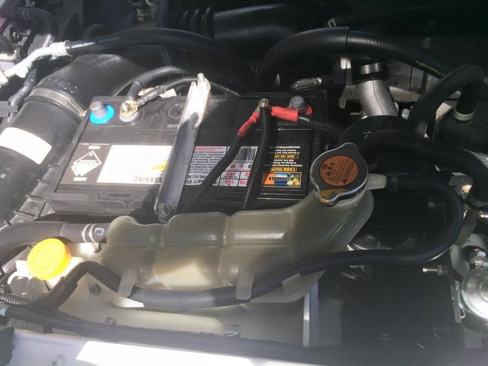 Car battery with jump starter cables and fluid reservoirs inside an engine bay Car battery with jump starter cables and fluid reservoirs inside an engine bay