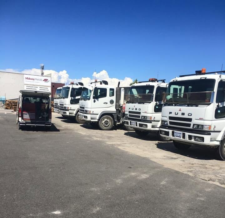 Row of white trucks parked in a lot under a bright blue sky Row of white trucks parked in a lot under a bright blue sky