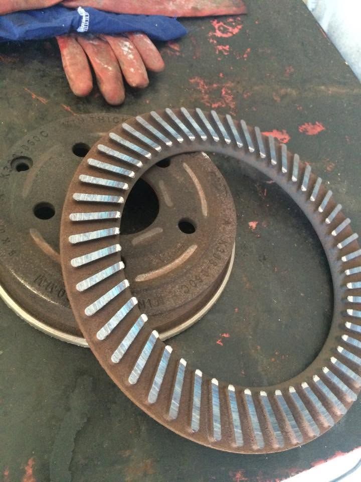 Rusty metal ring gear on a workbench beside a gloved hand and circular machine parts. Rusty metal ring gear on a workbench beside a gloved hand and circular machine parts.