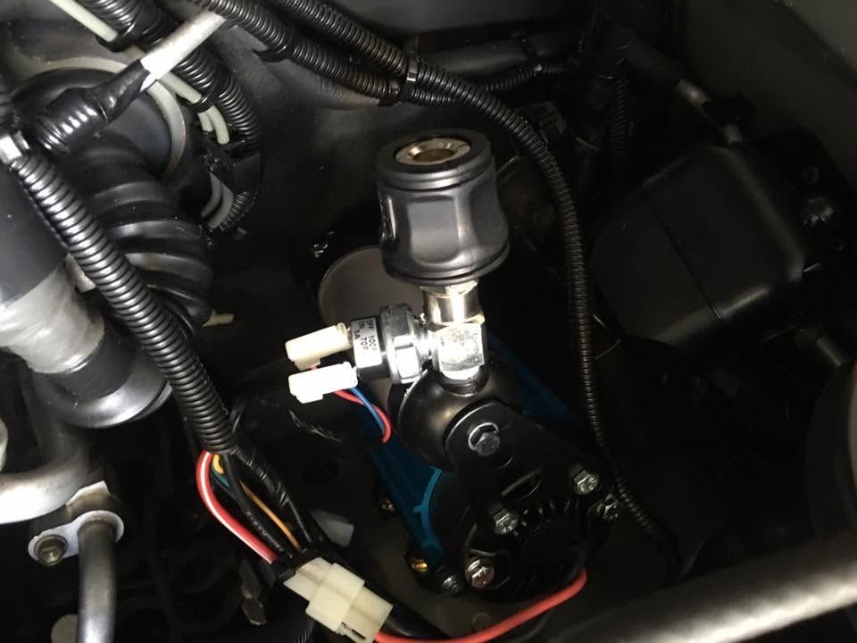 Close-up of a car engine bay with hoses, wiring, and a metal brake fluid reservoir. Close-up of a car engine bay with hoses, wiring, and a metal brake fluid reservoir.