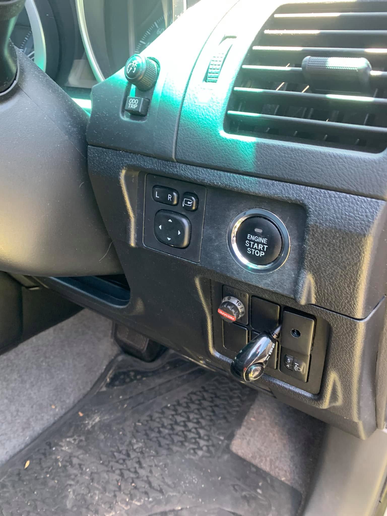 Car dashboard with headlight controls, air vents, and a plug-in device near the steering wheel