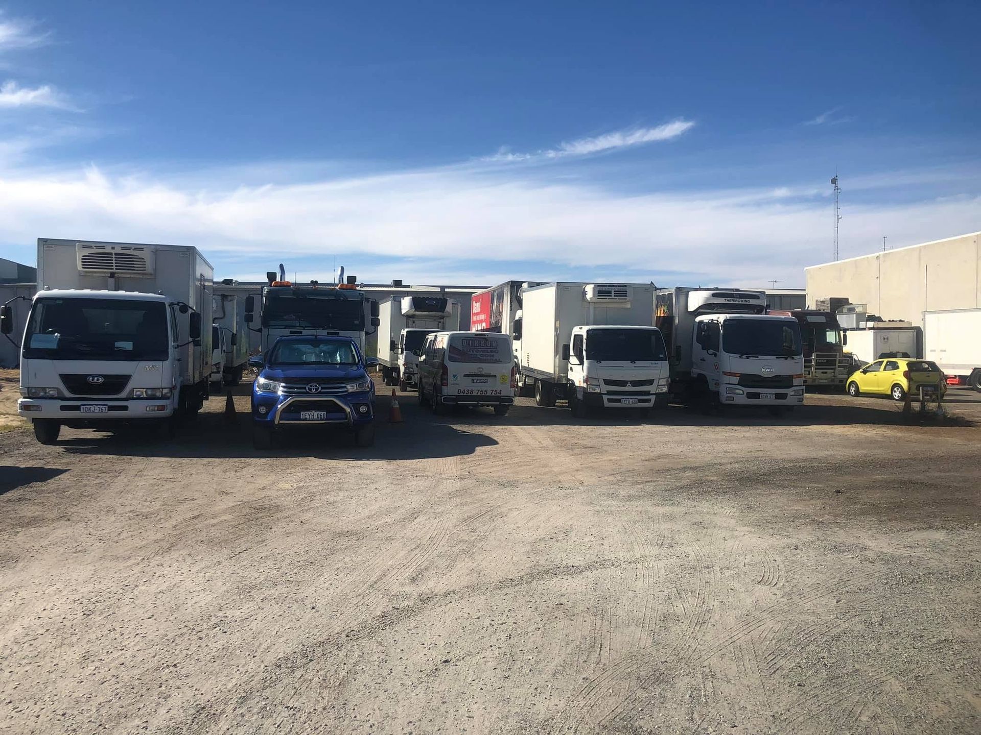 Row of parked trucks and vehicles in a gravel lot under a blue sky Row of parked trucks and vehicles in a gravel lot under a blue sky