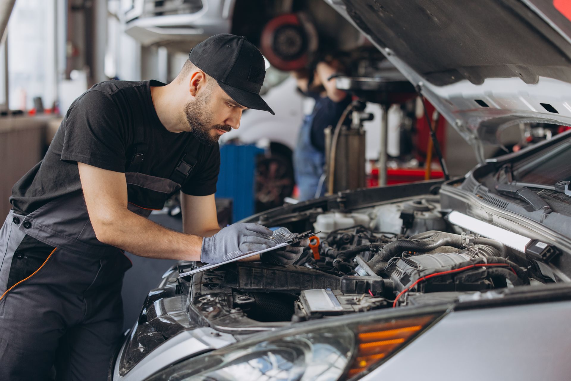 Mechanic inspecting a car engine in a garage with the hood open