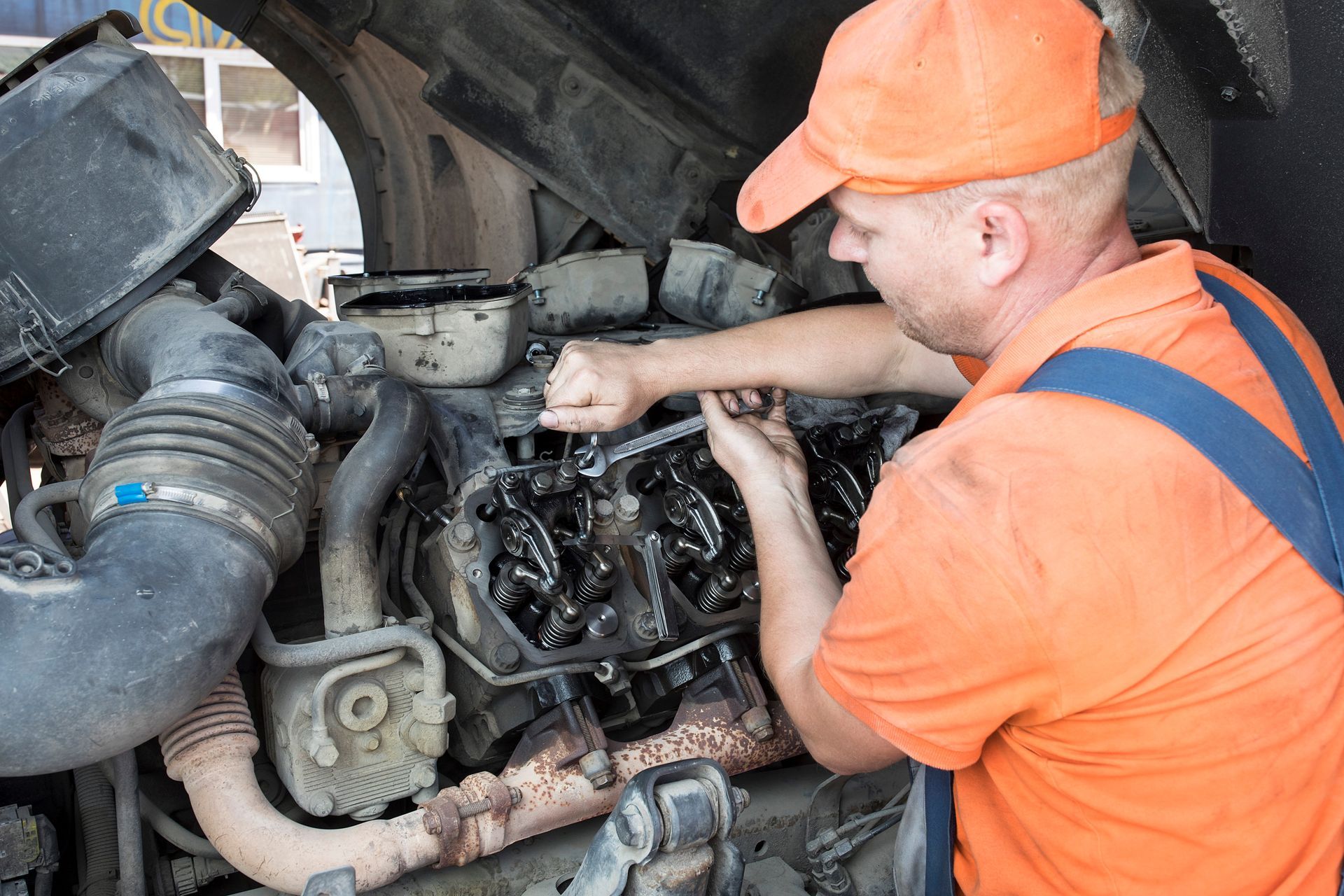 Pro automotive mechanic repair diesel engine. Mechanic using a tablet to inspect a muddy engine in a busy repair shop