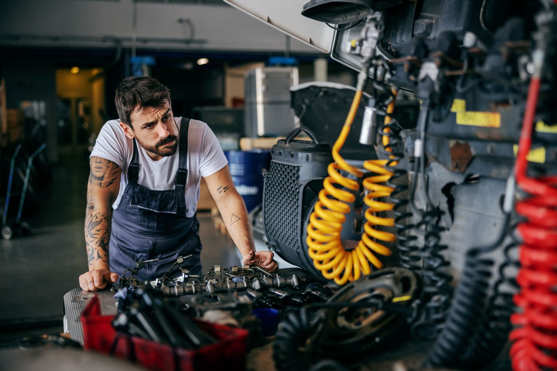 Mechanic inspecting truck components in a repair shop with tools on a workbench.