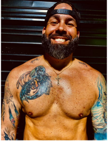 A shirtless man with a beard has a tattoo of a marine on his chest