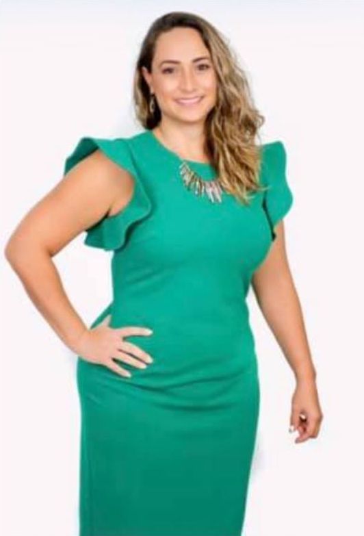 A woman in a green dress is standing with her hands on her hips.