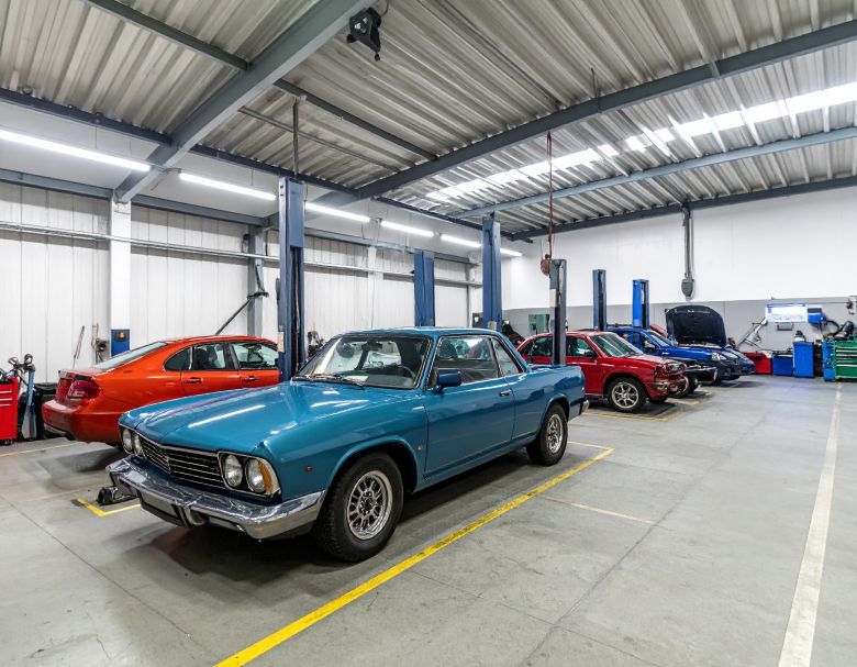 Cars being worked on in a well-lit auto repair shop with multiple lifts.