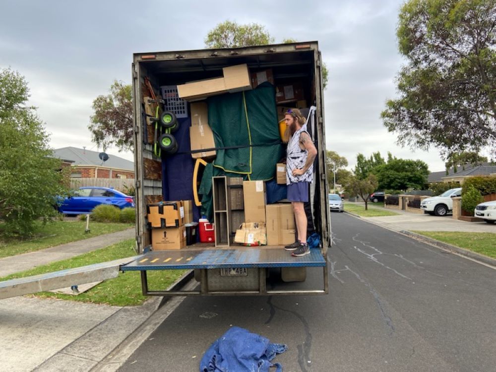 A Man is Standing in the Back of a Moving Truck — Bellarine Removals In Bendigo, VIC