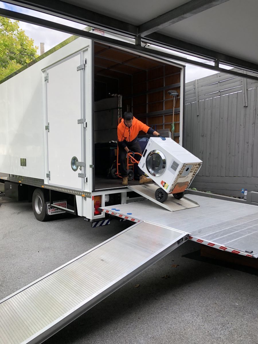 A Man is Loading a Washing Machine Into a Moving Truck — Bellarine Removals In Geelong, VIC