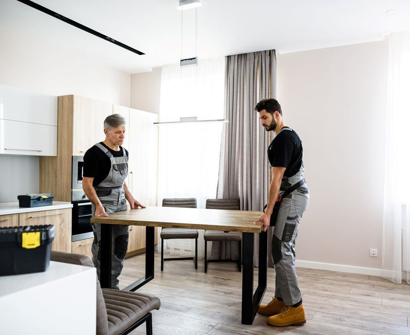 Two Men Are Standing Next to a Table in a Living Room — Bellarine Removals In Warrnambool, VIC
