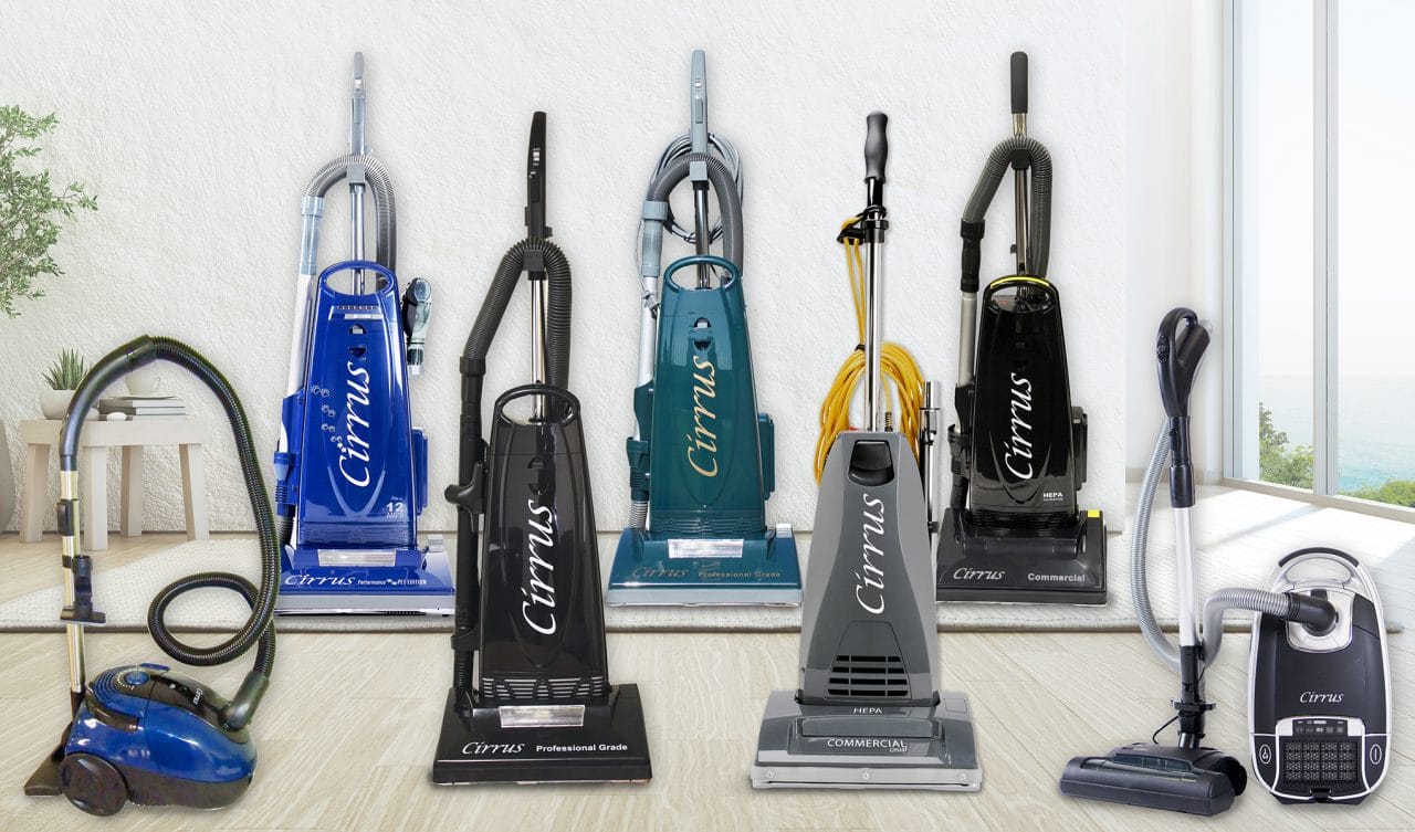 A line of various colored upright and canister vacuum cleaners against a bright background.
