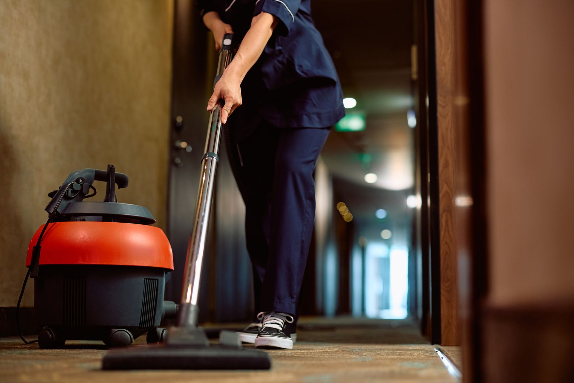 Close up of woman vacuuming hallway while working as maid in a hotel