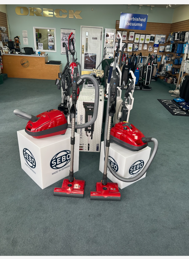 Two red SEBO vacuum cleaners displayed in a vacuum cleaner store.
