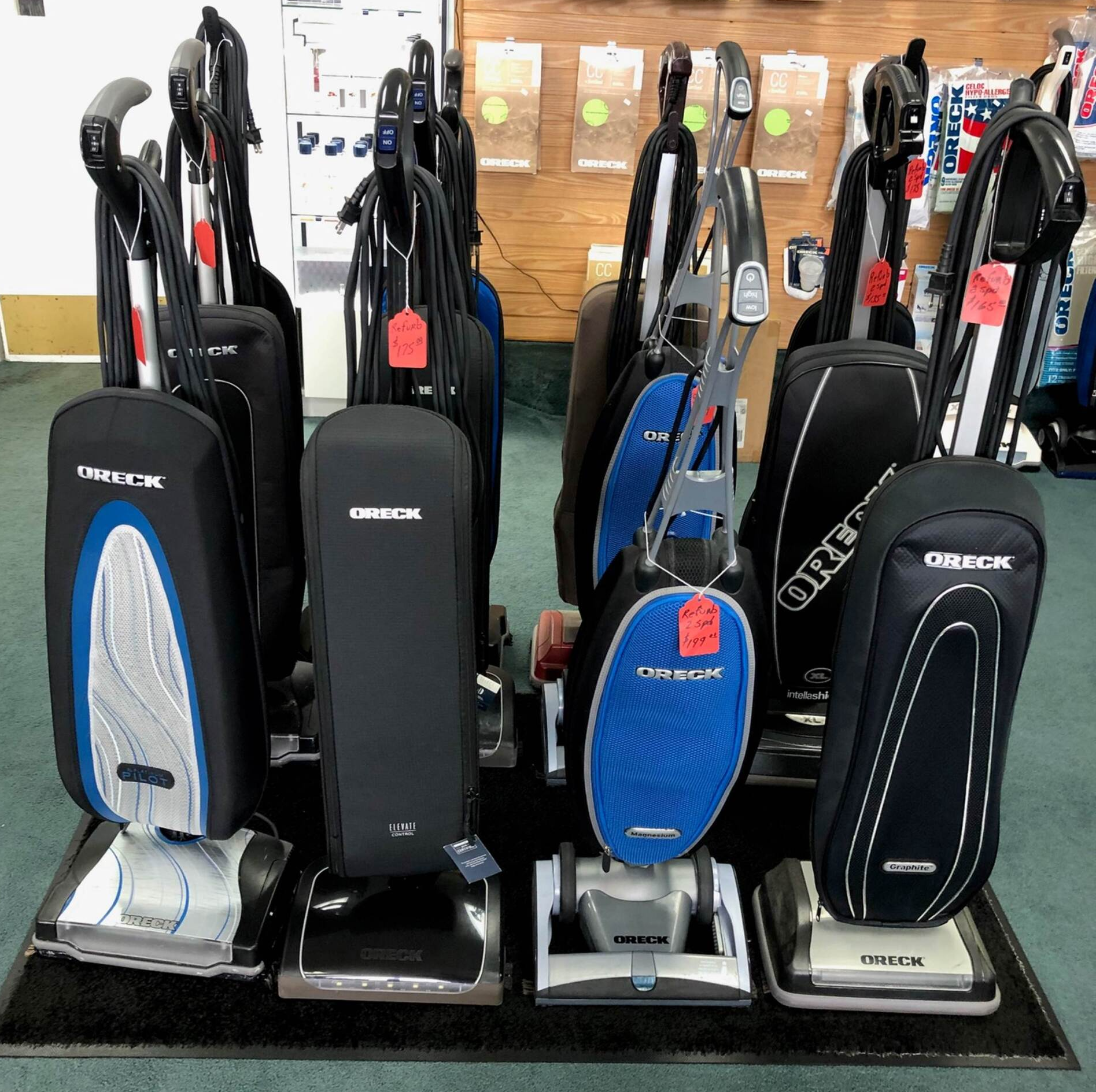 Vacuum cleaners on display in a store. Black and blue with silver bases.