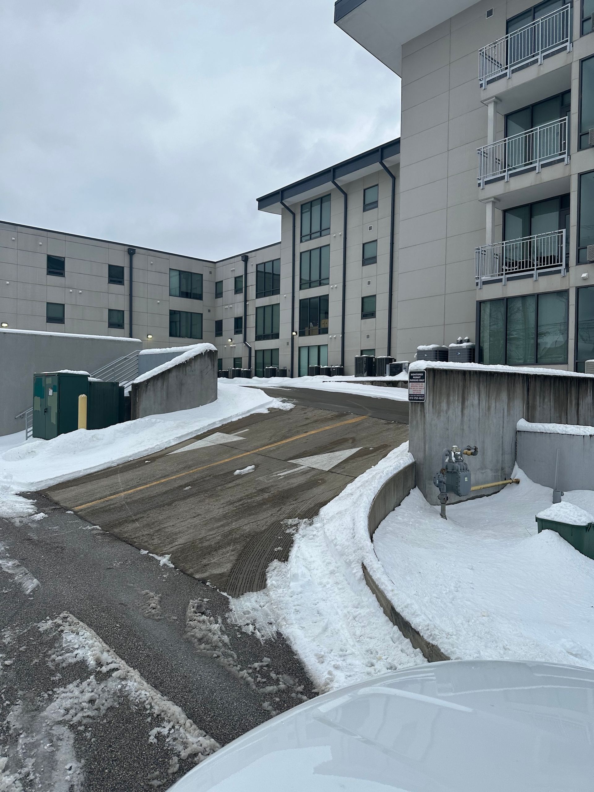 Snow-covered driveway beside modern apartment buildings
