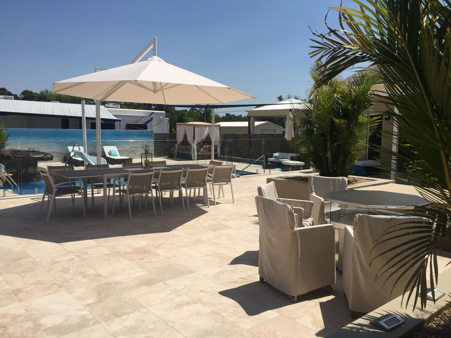 Outdoor patio with tables, chairs, and large umbrellas in a sunny setting.