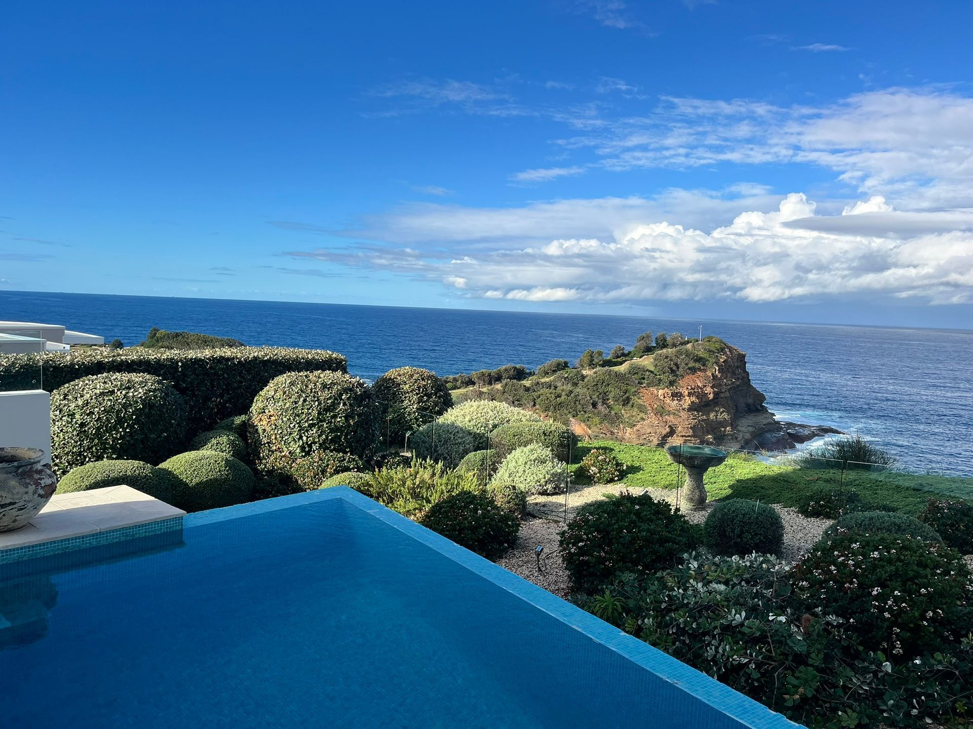 Infinity pool overlooking the ocean and rocky coastline under a bright blue sky — Divine Landscape Creations in Berkeley Vale, NSW