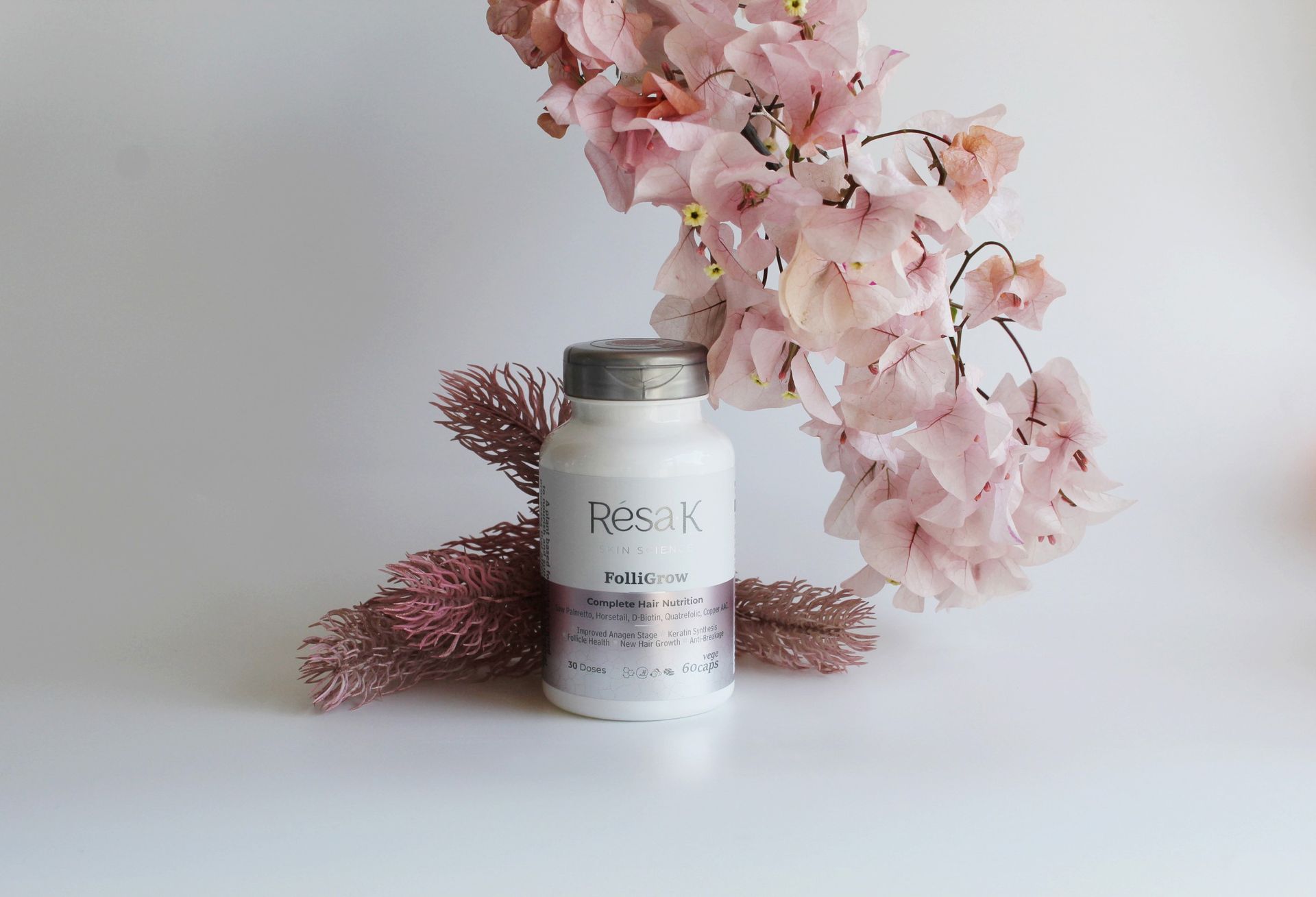 A bottle of pills is sitting next to a bunch of pink flowers.