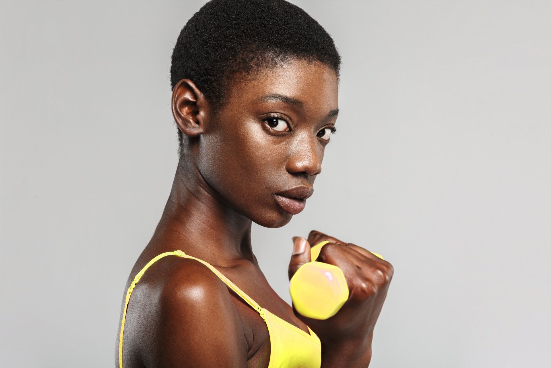 A woman in a yellow bra is holding a yellow object in her hands.