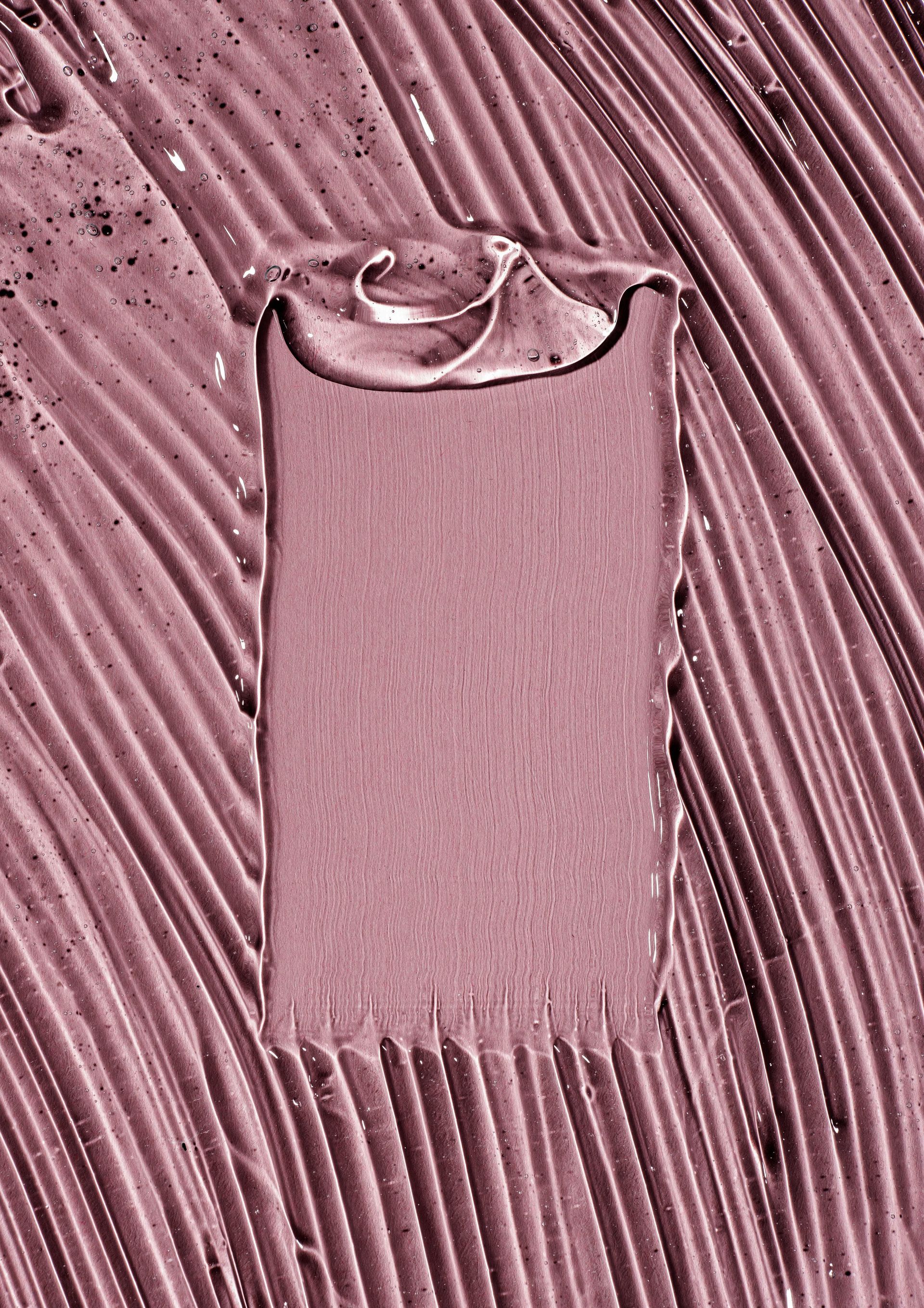 A close up of a few drops of liquid on a white surface.