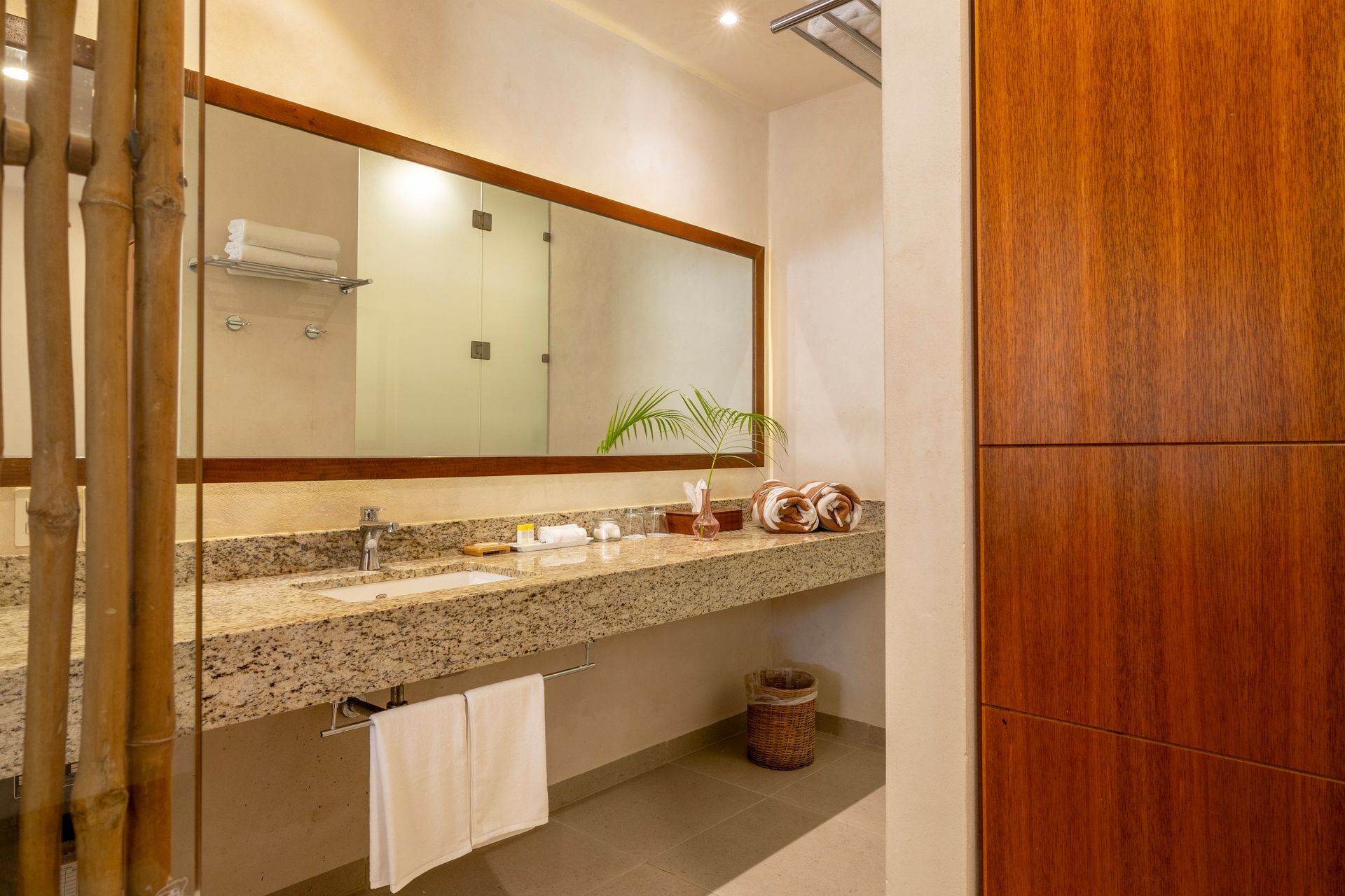 Bathroom with a granite countertop, large mirror, and bamboo accents.