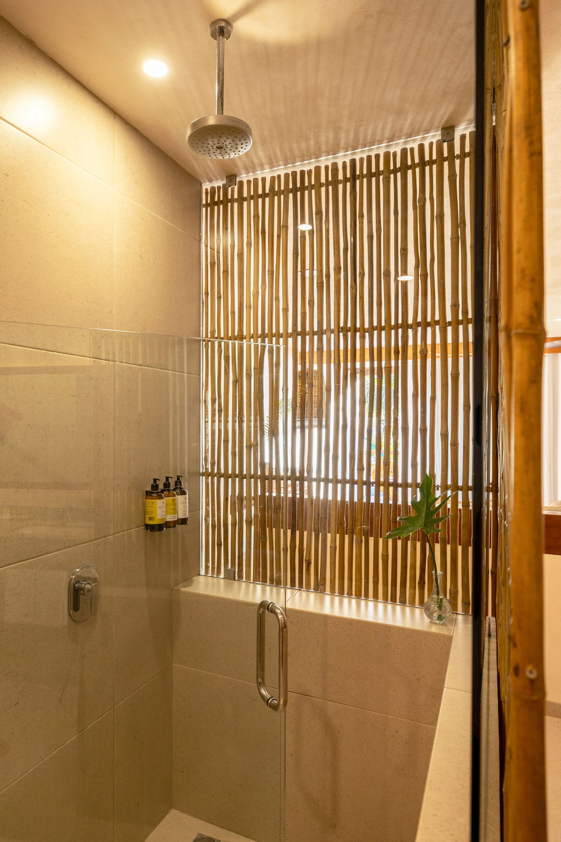 Shower with bamboo screen, gray tiles, glass door, and silver shower head.