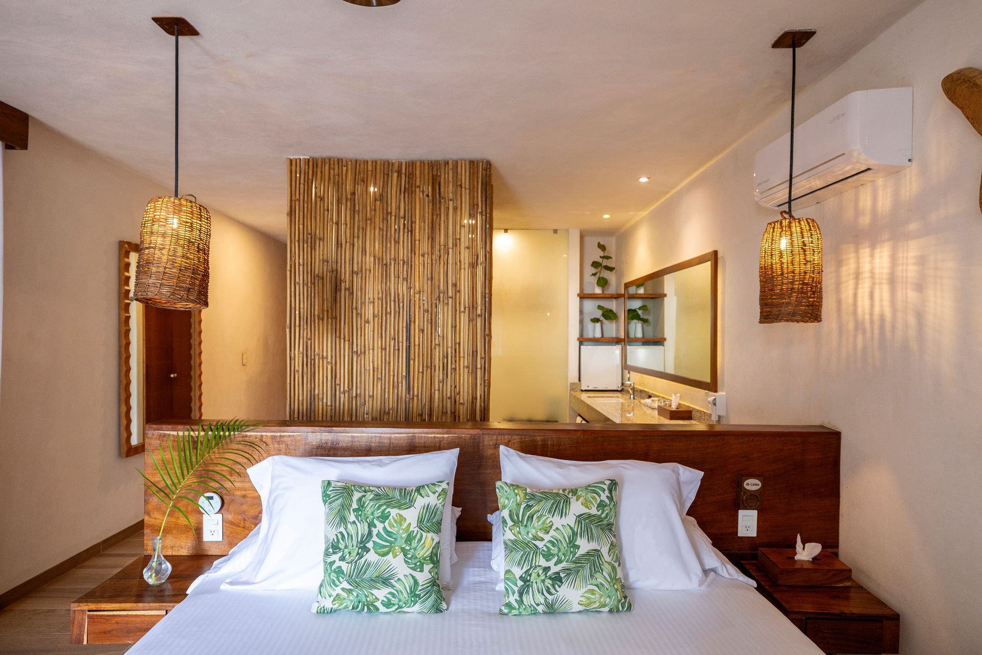 Bedroom with wooden headboard, two pendant lights, and a view into a bathroom.