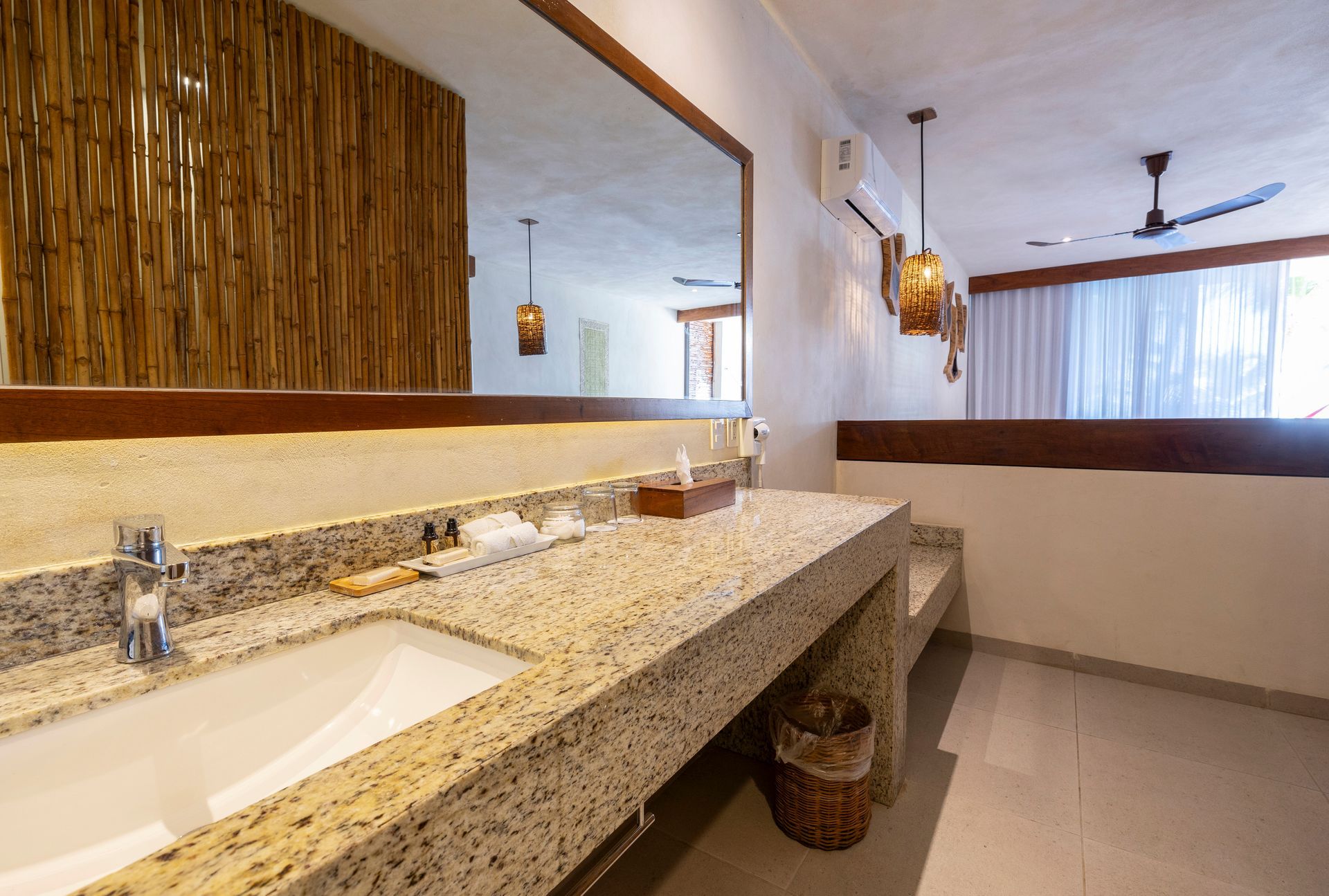 Bathroom with stone countertop, large mirror, wooden accent wall, and ceiling fan.