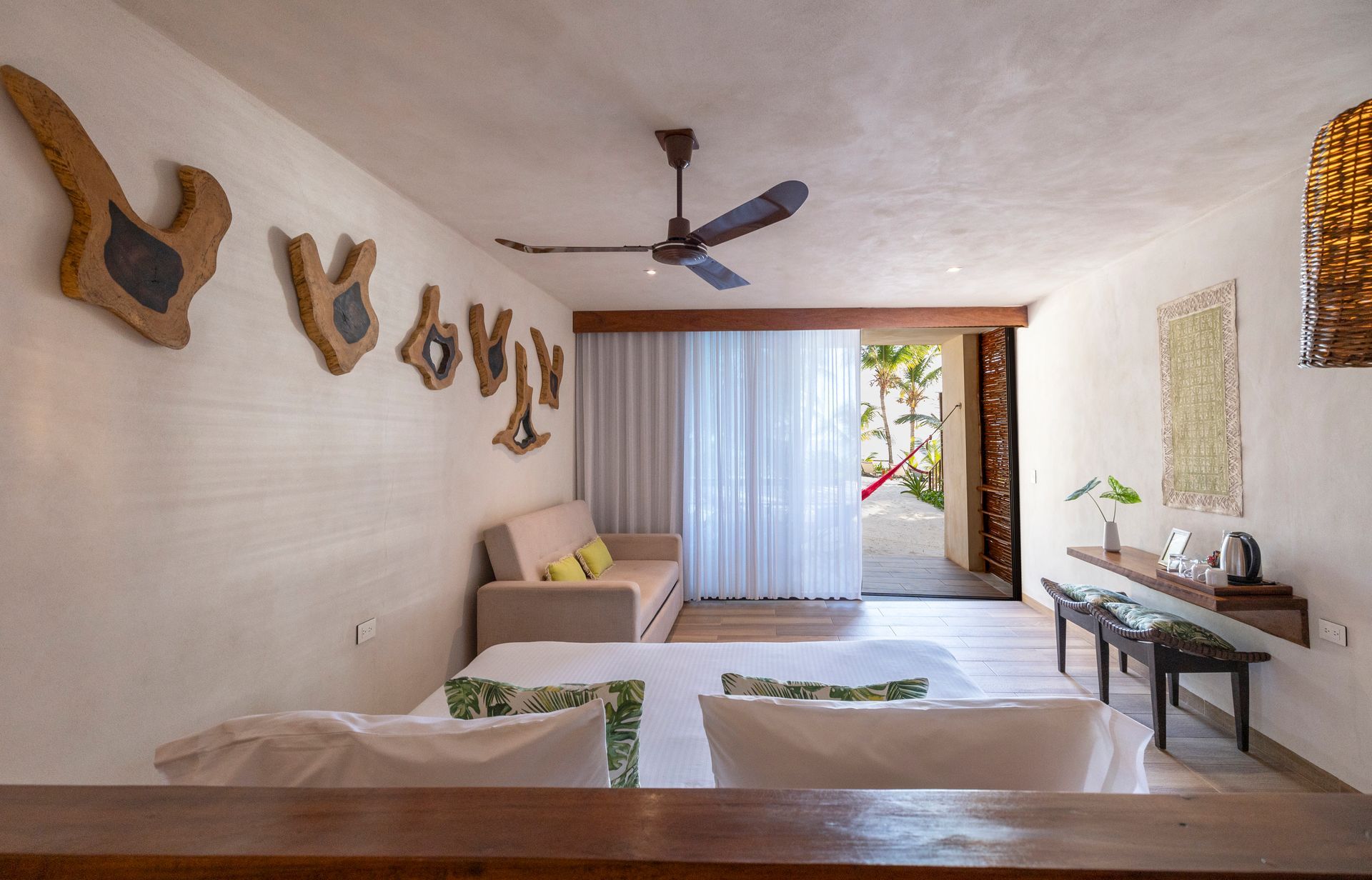 Bright hotel room interior with a sofa, bed, and open door to an outdoor area.