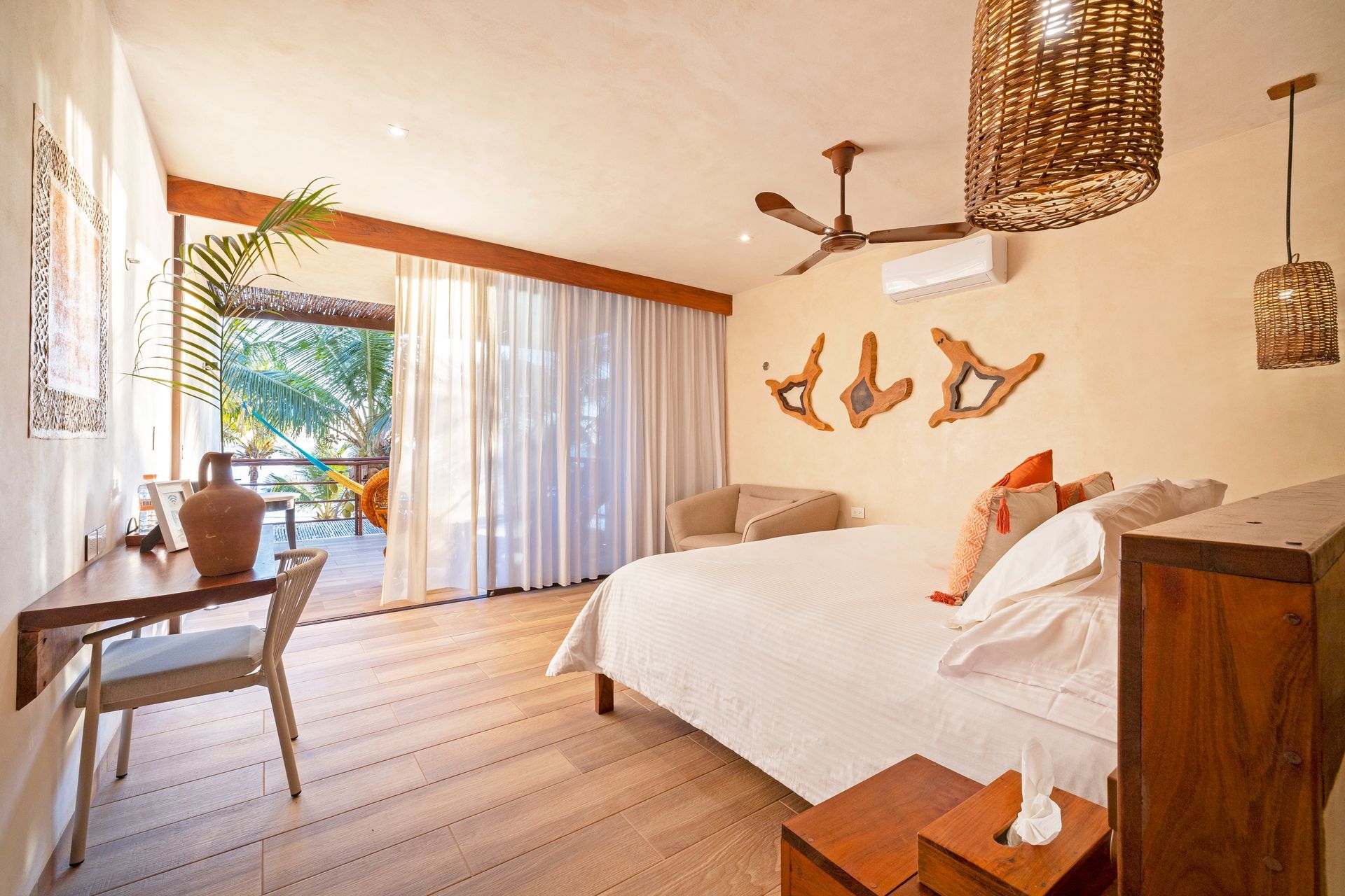 Bedroom with a bed, desk, and balcony view, featuring natural wood and light colors.