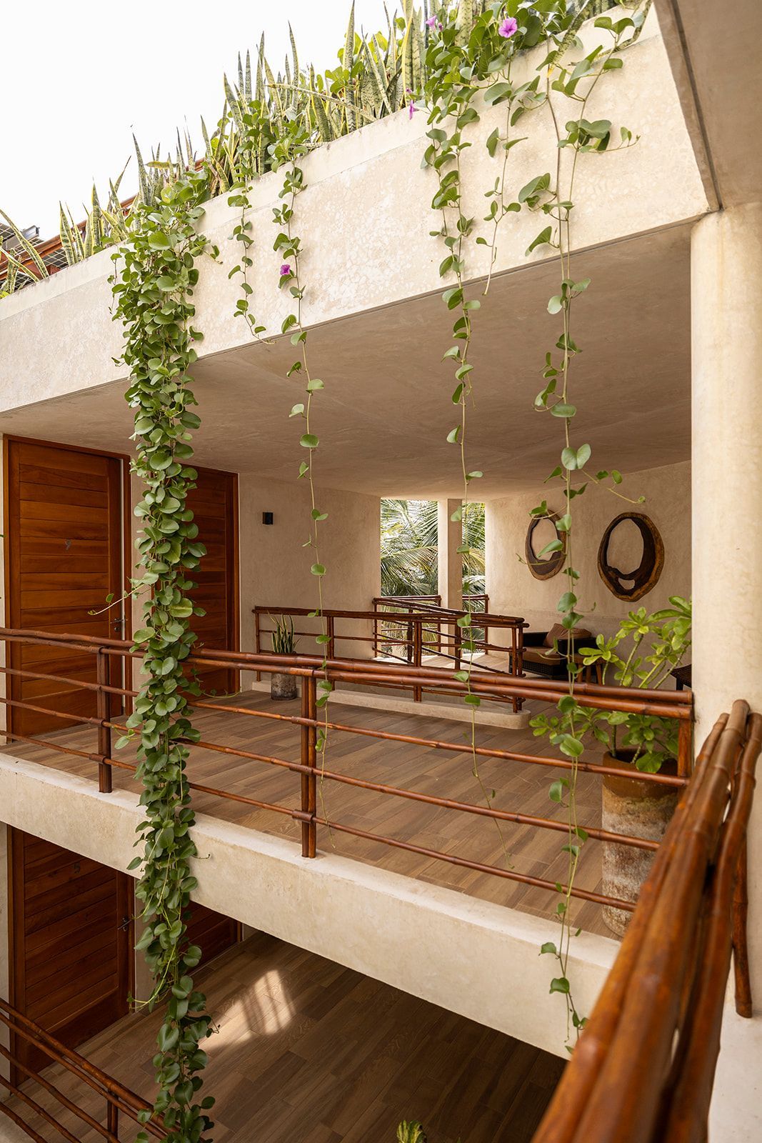 Balcony with wooden railing and doors, with trailing vines and rooftop garden.