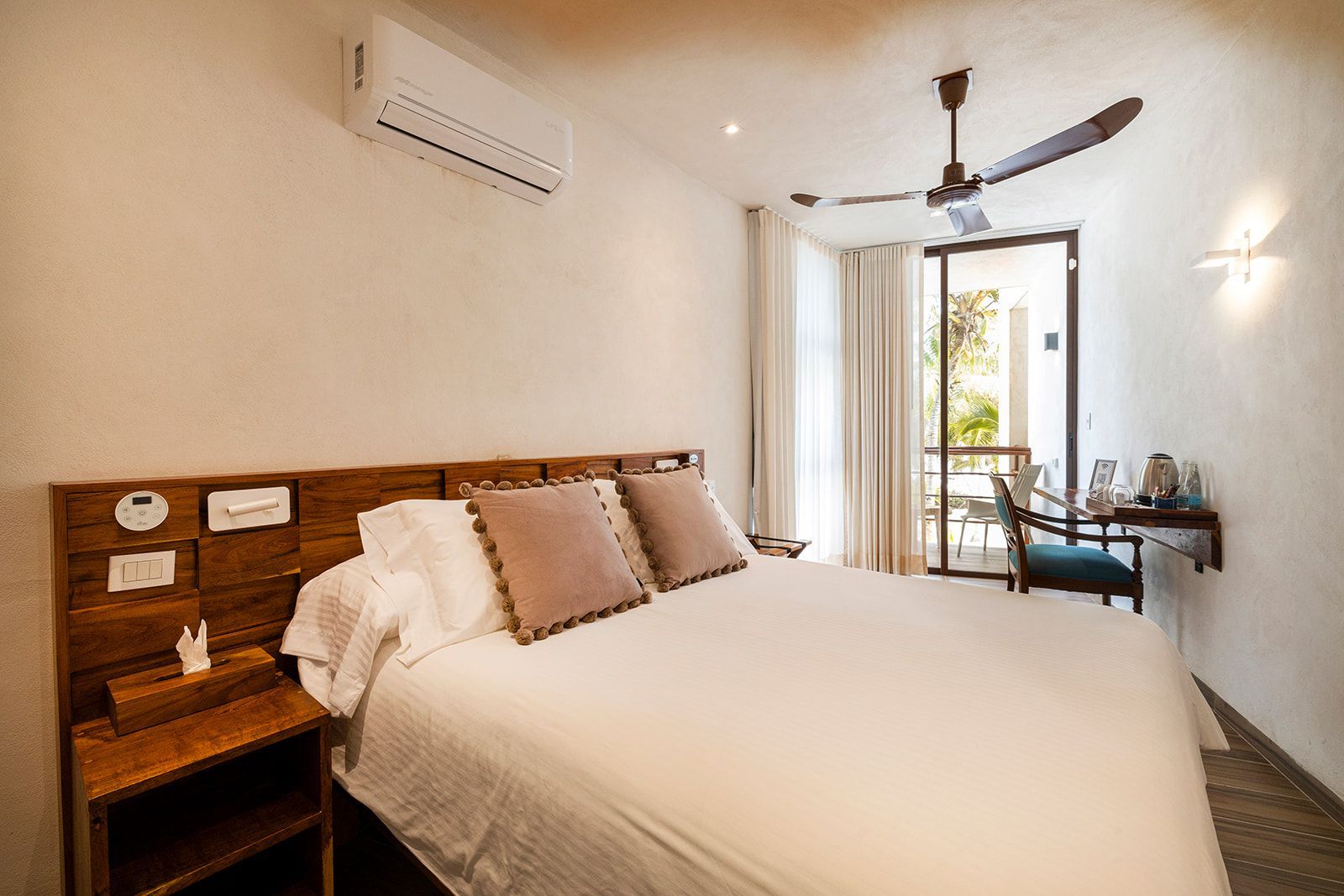 Bedroom with bed, pillows, nightstand, open balcony door, and air conditioning.