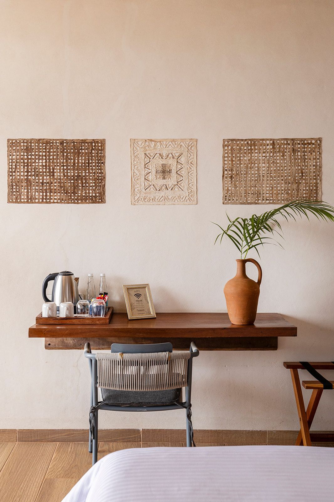Room interior with desk and chair, adorned with decorative wall panels, a vase, and a tea set.